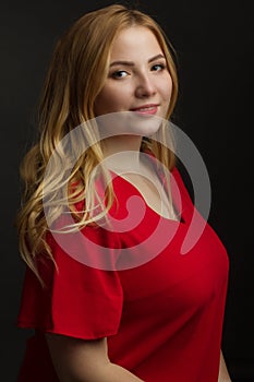 A blonde girl with an overweight plus size, a red overallposing on a dark Studio background
