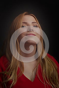 A blonde girl with an overweight plus size, a red overallposing on a dark Studio background