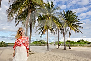 Blonde girl with palm trees in sands of the beach