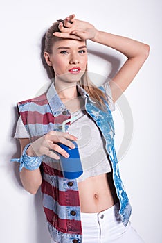 Blonde girl in patriotic denim vest holding soda can with straw and looking at camera