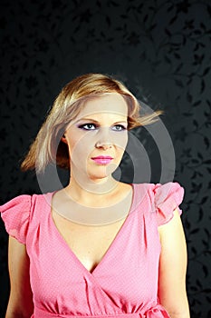 Blonde girl in a pink dress in the studio