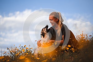 Blonde girl playing with puppy spanish mastiff in a field of yellow flowers