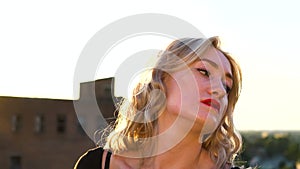 Blonde girl posing on roof at sunset