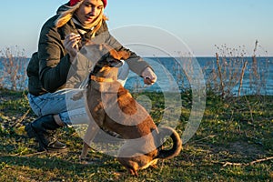 A blonde girl with a purebred dog from the shelter. Playing with a dog on the seashore.