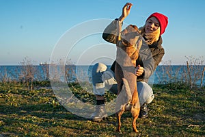 A blonde girl with a purebred dog from the shelter. Playing with a dog on the seashore.