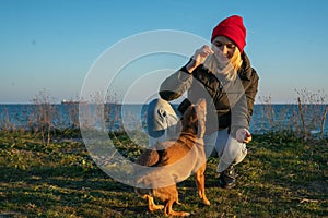 A blonde girl with a purebred dog from the shelter. Playing with a dog on the seashore.