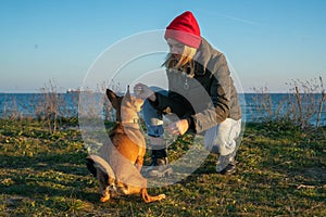 A blonde girl with a purebred dog from the shelter. Playing with a dog on the seashore.