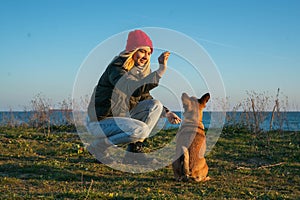 A blonde girl with a purebred dog from the shelter. Playing with a dog on the seashore. Friendship of a dog and a person