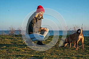 A blonde girl with a purebred dog from the shelter. Playing with a dog on the seashore. Friendship of a dog and a person