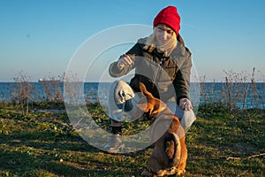 A blonde girl with a purebred dog from the shelter. Playing with a dog on the seashore. Friendship of a dog and a person