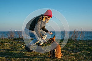 A blonde girl with a purebred dog from the shelter. Playing with a dog on the seashore. Friendship of a dog and a person