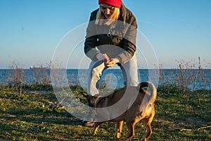 A blonde girl with a purebred dog from the shelter. Playing with a dog on the seashore. Friendship of a dog and a person