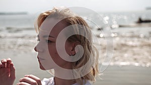 Blonde girl sensually dancing on a background of the sea in white clothes