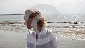 Blonde girl sensually dancing on a background of the sea in white clothes