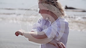 Blonde girl sensually dancing on a background of the sea in white clothes