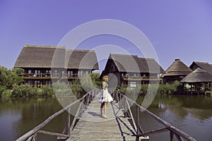 Blonde girl  standing on a wooden dock above the river