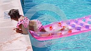 Blonde girl swims in the pool on an inflatable mattress