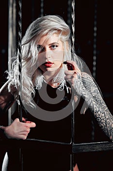 Blonde girl with tattoo on dark background.