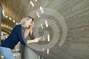 Blonde girl using smartphone in monophonic background.