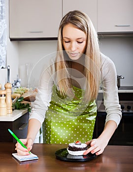 Blonde girl weighing cakes on kitchen scales