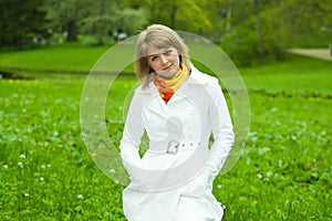 Blonde girl in white on a background of green gras