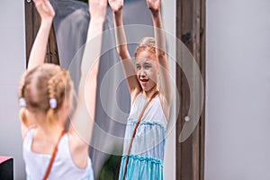 Blonde girl in white and blue dress playing in the playground in the summer park of entertainments
