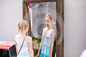 Blonde girl in white and blue dress playing in the playground in the summer park of entertainments