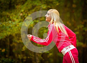 Blonde girl young woman running jogging in autumn fall forest park