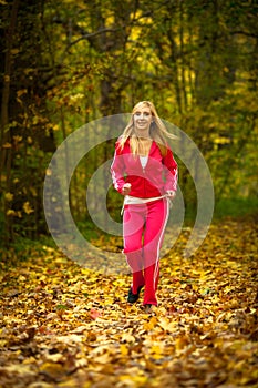 Blonde girl young woman running jogging in autumn fall forest park