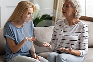 Blonde grown up daughter arguing with nervous old mature mother.