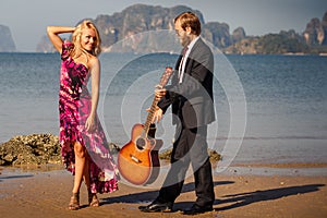 Blonde and guitarist side-view on beach