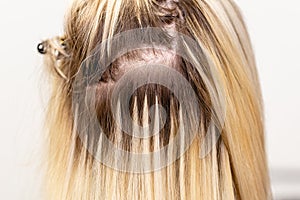 Blonde hair extensions procedure in beauty salon