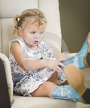 Blonde Haired Blue Eyed Little Girl Putting on Cowboy Boots