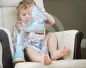 Blonde Haired Blue Eyed Little Girl Putting on Cowboy Boots