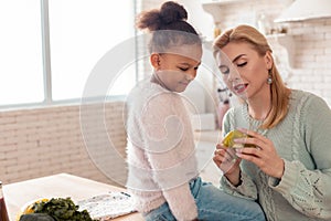 Blonde-haired mother telling her daughter about healthy vegetables