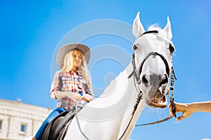 Blonde-haired teenage girl enjoying her horse riding lesson