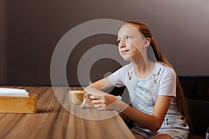 Blonde-haired teenager drinking decaf latte in cafe