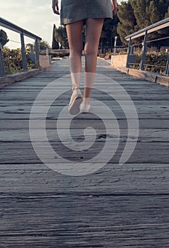 Blonde-haired woman strolling relaxed on wooden bridge de-stressing from city life