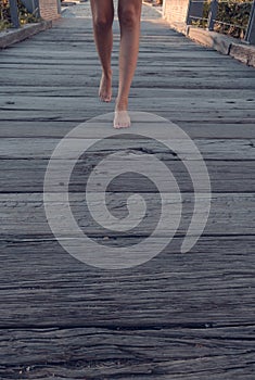 Blonde-haired woman strolling relaxed on wooden bridge de-stressing from city life