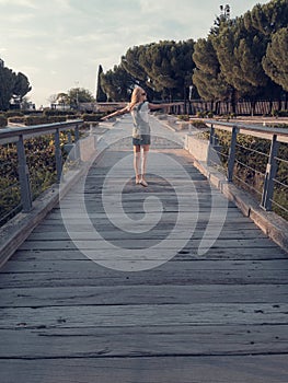 Blonde-haired woman strolling relaxed on wooden bridge de-stressing from city life