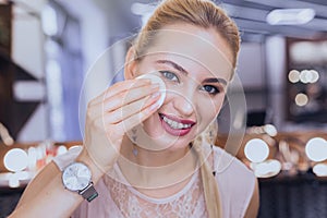 Blonde-haired woman wearing dental brackets taking makeup off