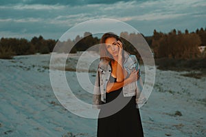 blonde haired young woman posing in sands of desert lit by red setting sun light