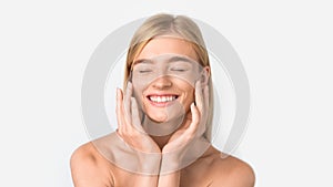 blonde lady caring for her facial skin applying moisturizer, studio