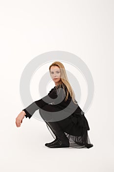 Blonde lady sitting on her haunches in profile on light gray background