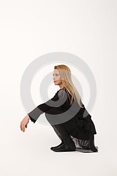 Blonde lady sitting on her haunches in profile on light gray background