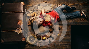 Blonde little boy resting with leaf on stomach lies on wooden floor in autumn leaves. The biggest discounts for all