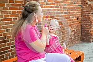 Blonde little girl with cochlear implant playing with her mother outdoor. Hear impairment deaf and health concept