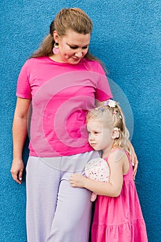 Blonde little girl with cochlear implant playing with her mother outdoor. Hear impairment deaf and health concept