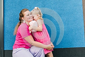 Blonde little girl with cochlear implant playing with her mother outdoor. Hear impairment deaf and health concept