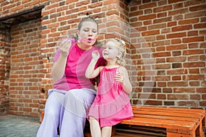 Blonde little girl with cochlear implant playing with her mother outdoor. Hear impairment deaf and health concept